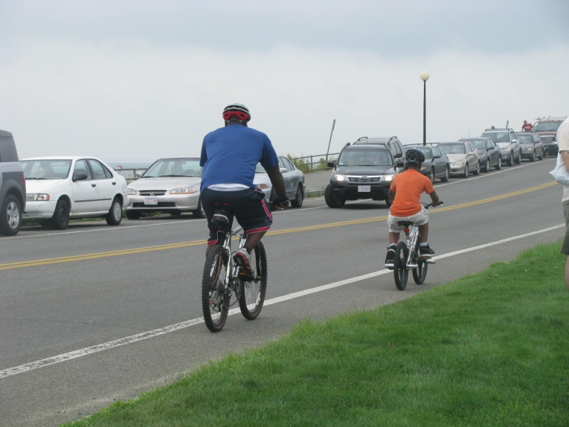 Father and son riding bicycles on the shoulder wearing helmets